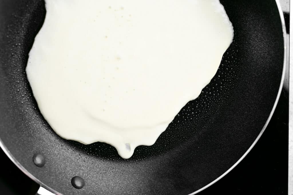 crepe batter spreading out into the frying pan