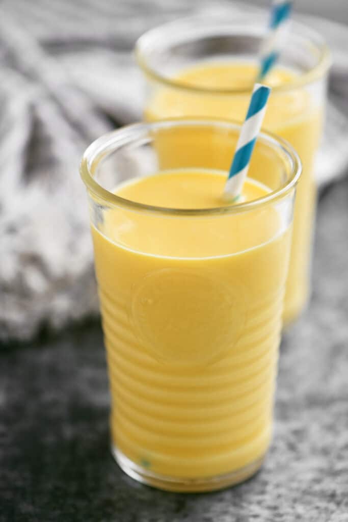 2 mango smoothies in glasses with straws