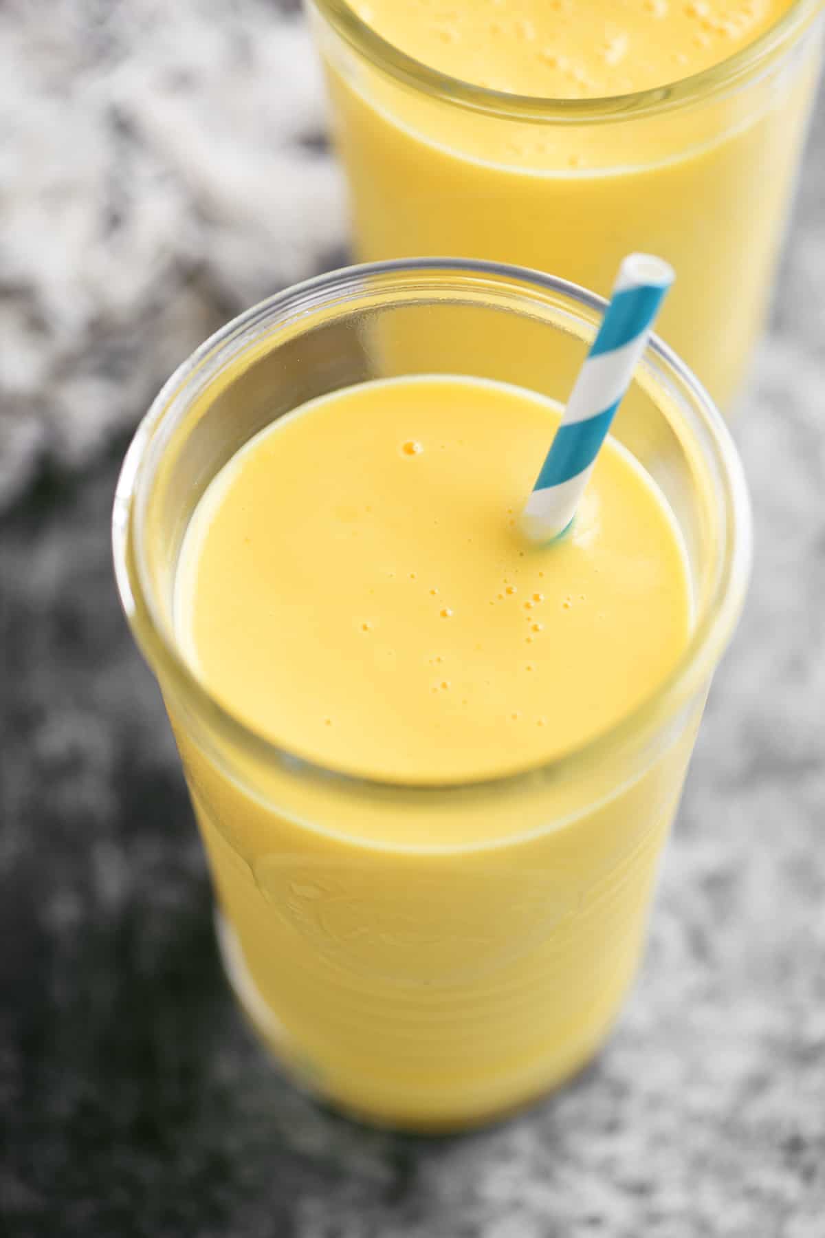 a mango smoothie with a blue and white straw