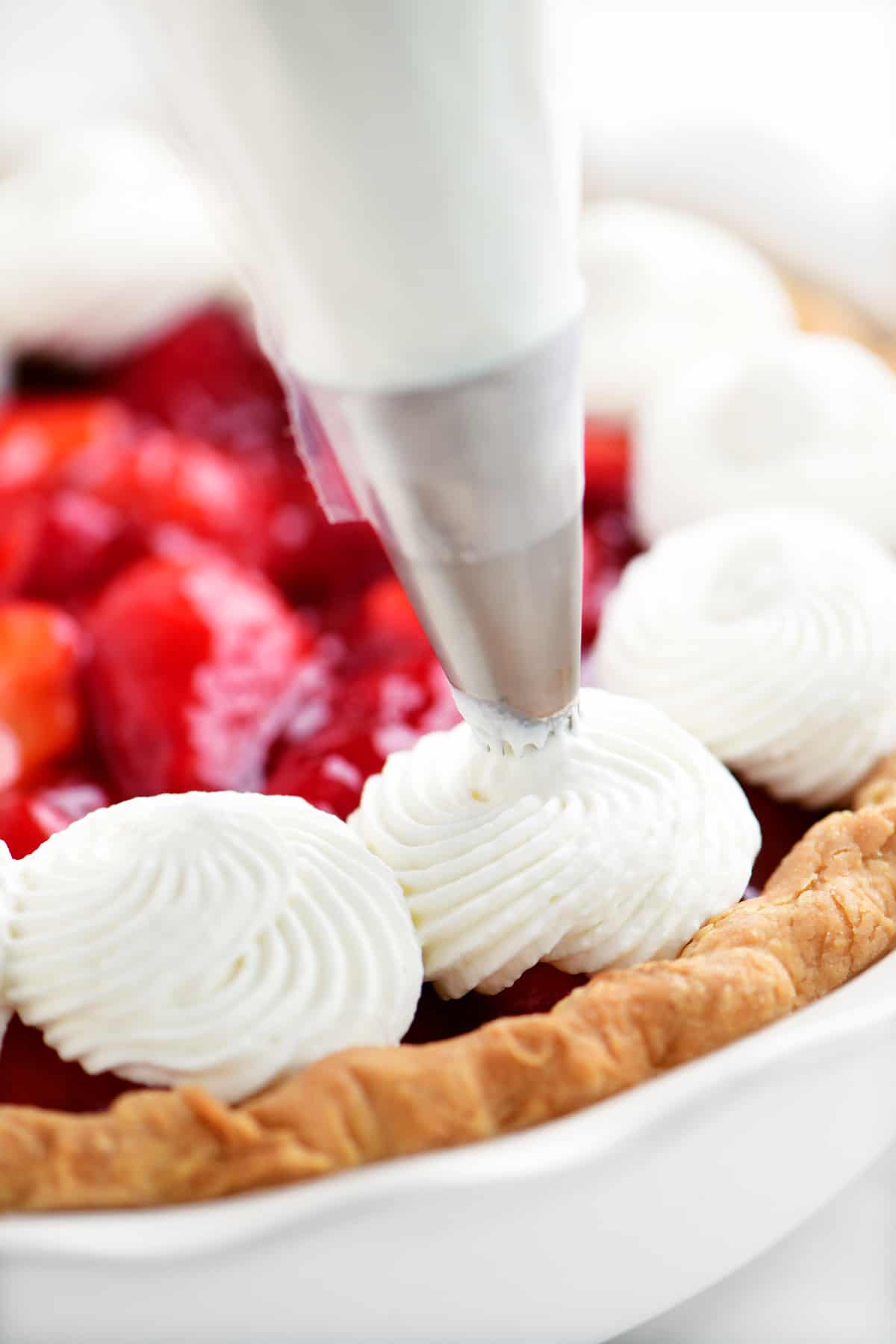 a piping bag piping whipped cream on to a pie