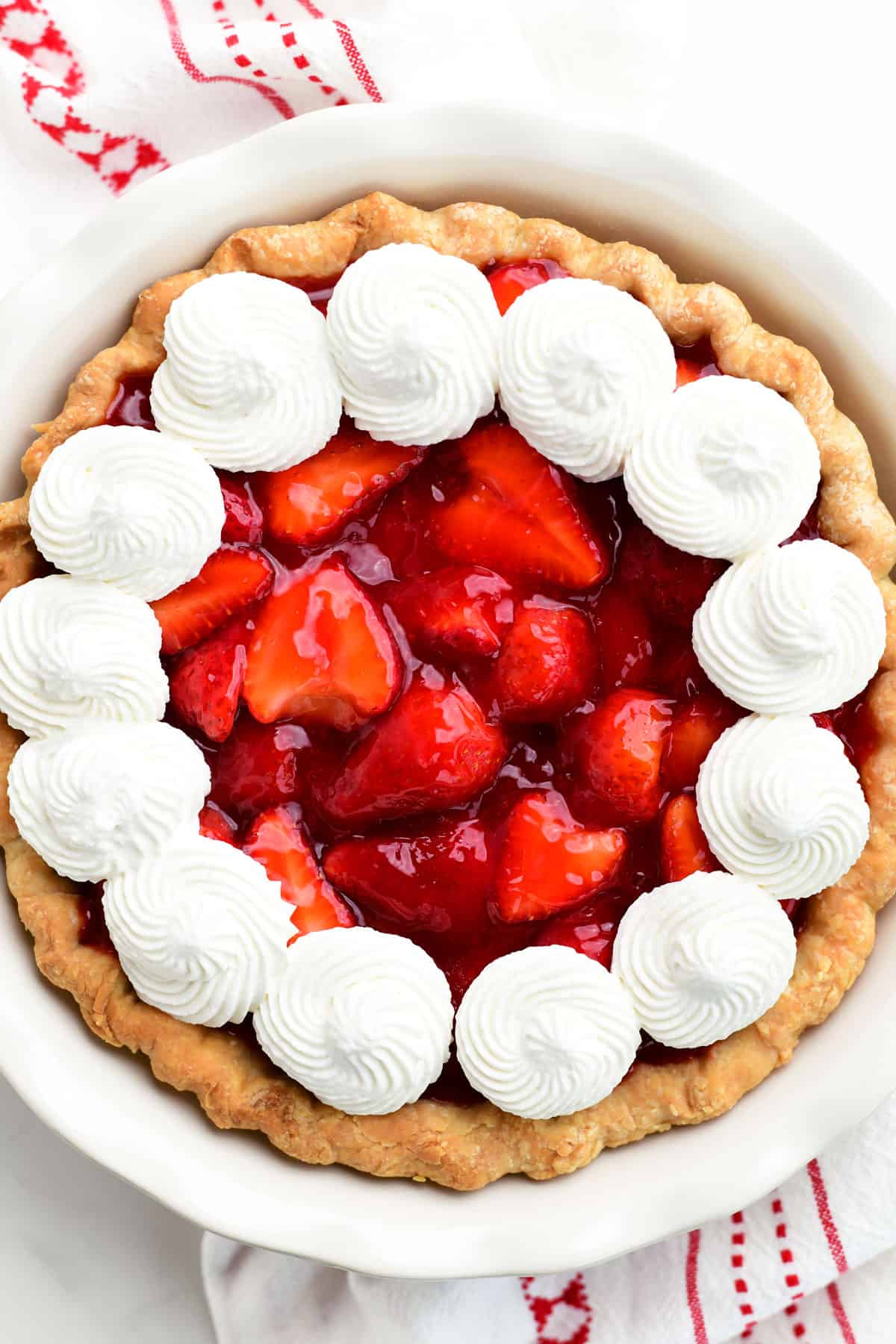 a strawberry pie with whipped cream dollops on top