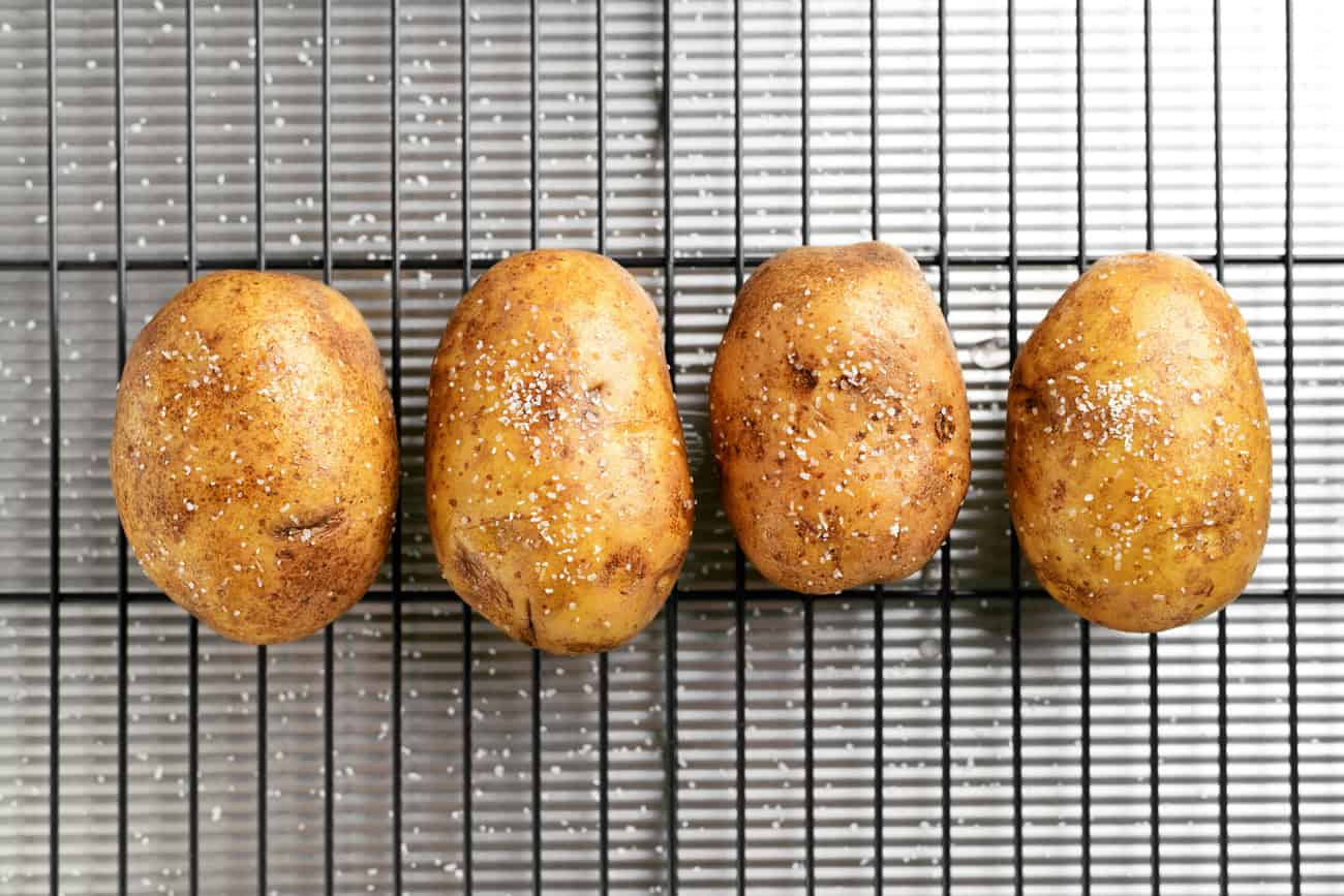 4 potatoes sprinkled with salt arranged on a baking rack