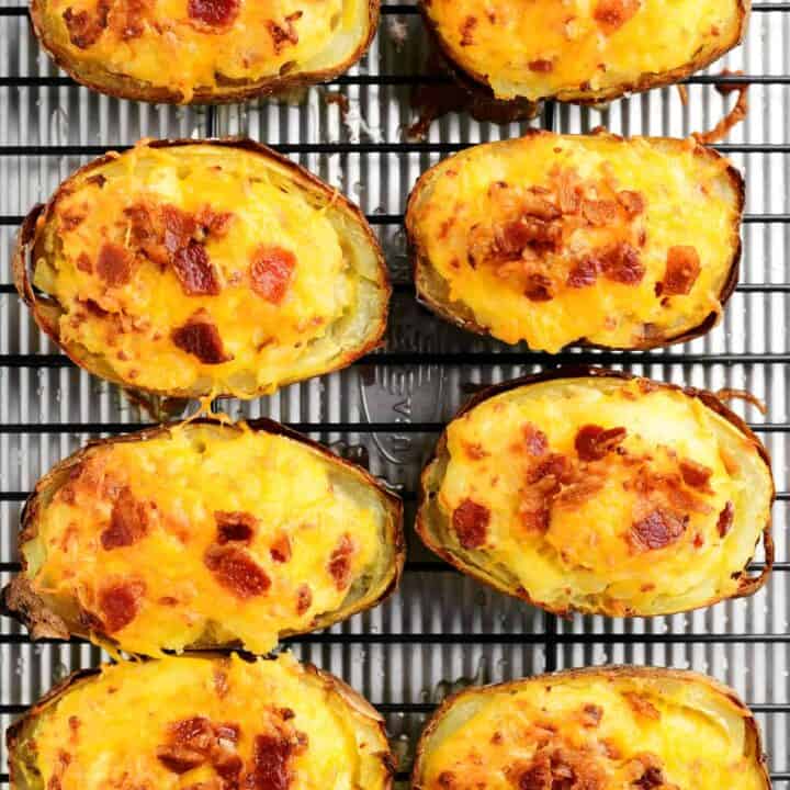 eight baked potato halves with cheddar and bacon arranged on a cooking rack