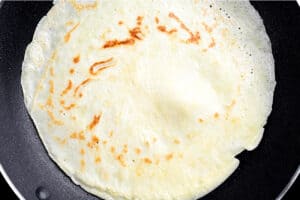 a browned crepe in a frying pan