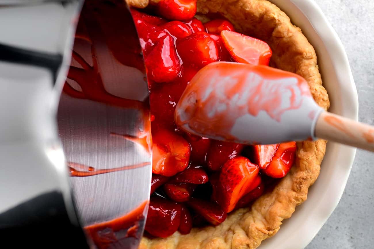 pouring strawberries into the pie crust
