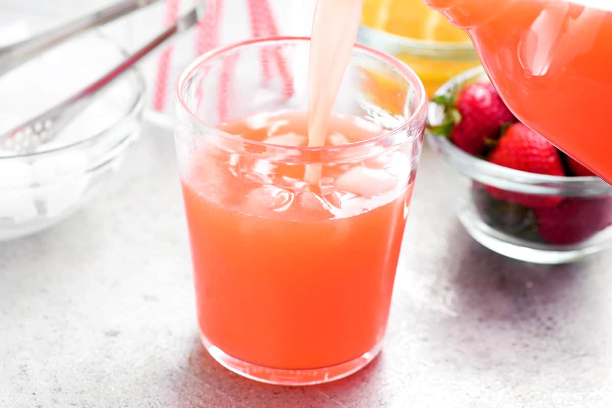 pour strawberry lemonade into a glass of ice