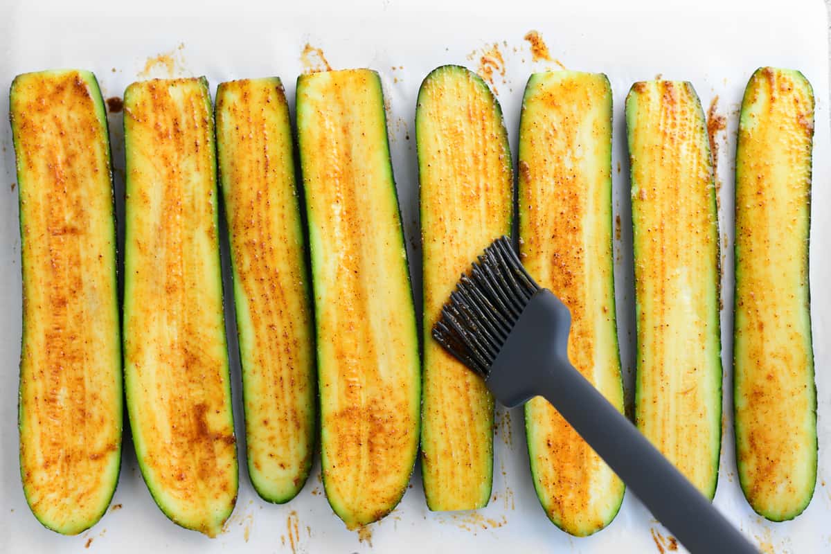 Brushing marinade on sliced zucchini.
