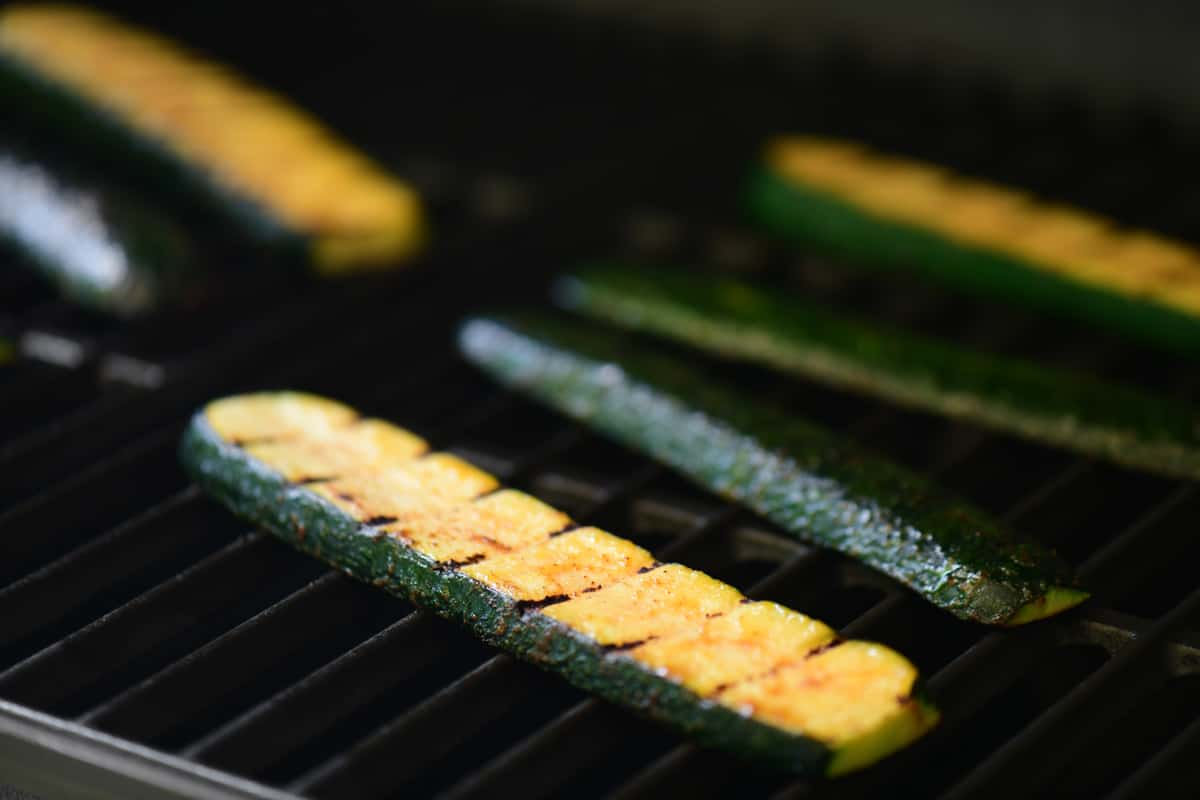 six zucchini slices on the grill grates.