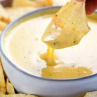 tortilla chip being dipped in queso