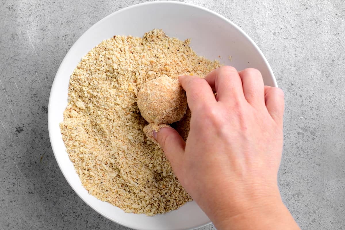 coating a ball of cheese with breadcrumbs