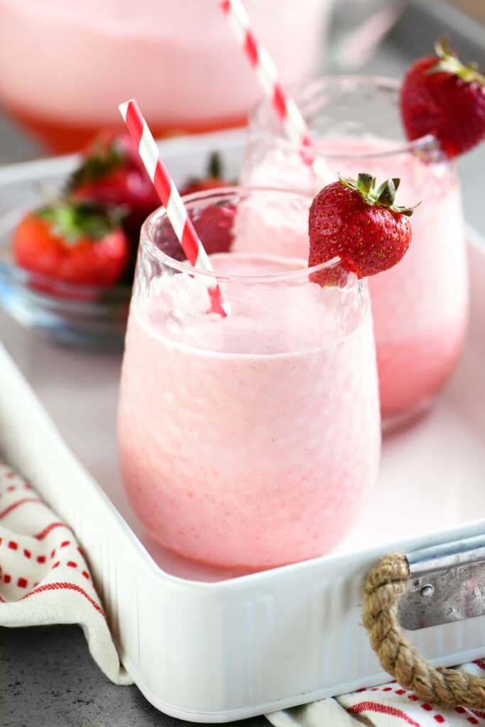 pink drink in two cups with strawberry garnish and striped straws