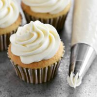cream cheese buttercream on a cupcake and in a piping bag
