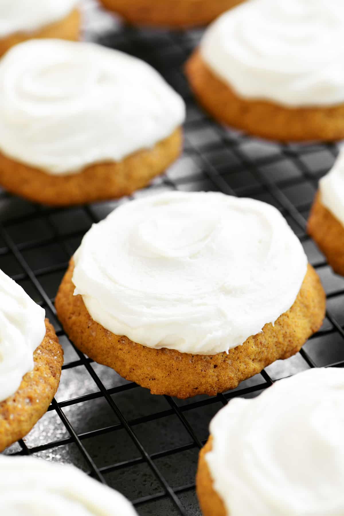 frosted pumpkin cookies on a rack