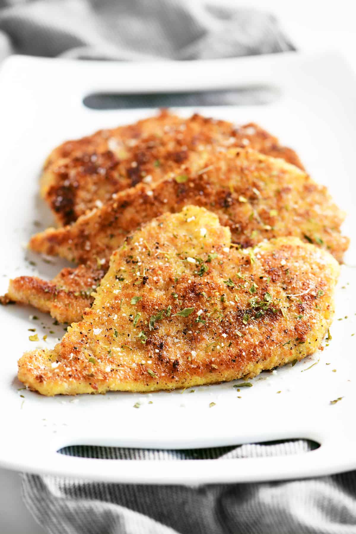 front view of crispy parmesan chicken on a white platter
