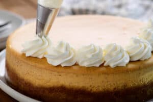 piping whipped cream on cheesecake