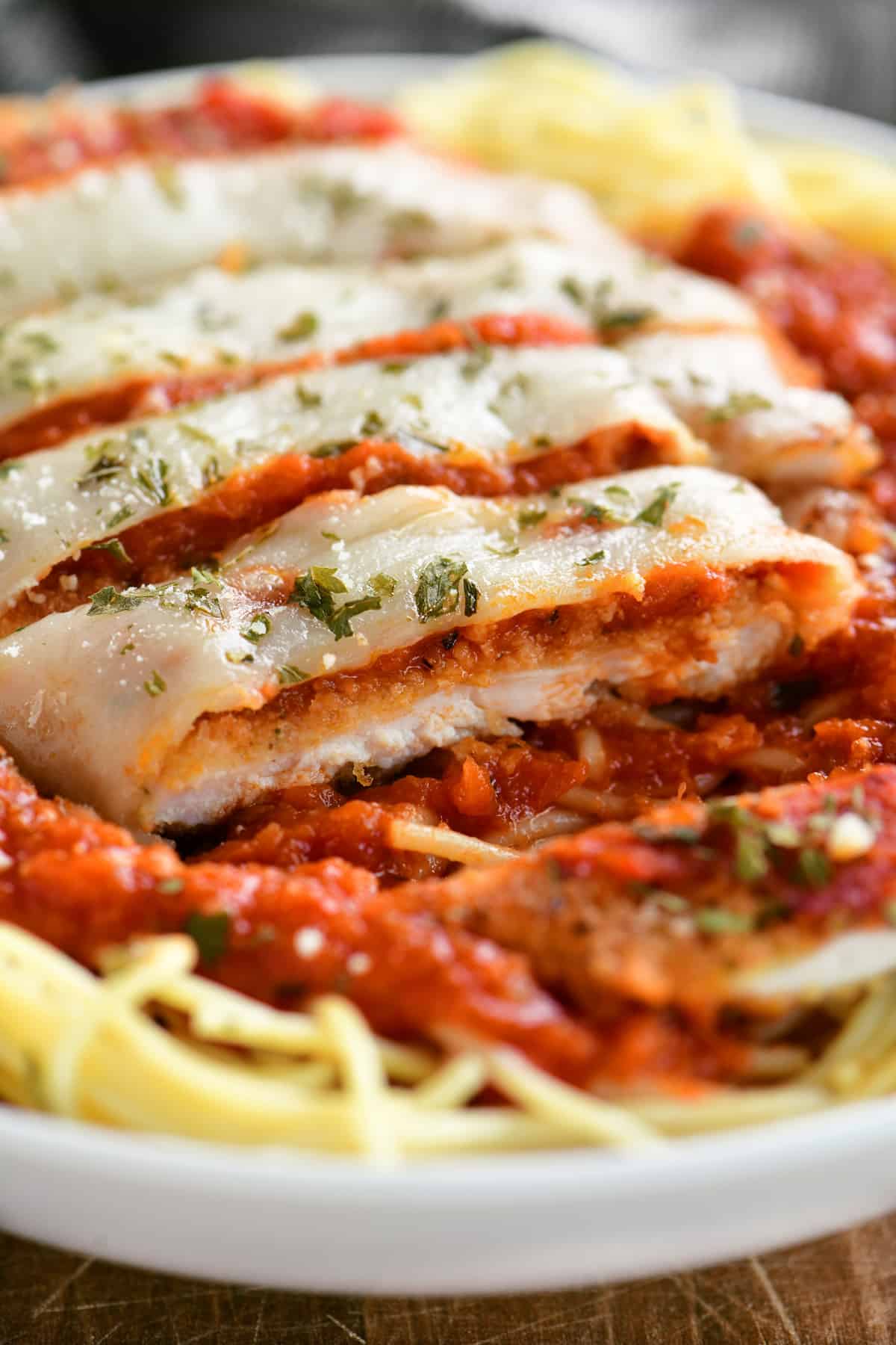 sliced chicken parmesan on pasta in a bowl
