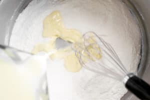 pouring ingredients into a pan and whisking