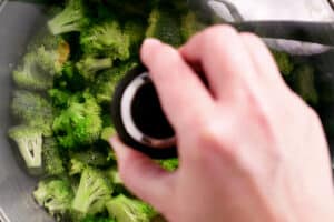 a hand placing a cover on a cooking pot filled with broccoli