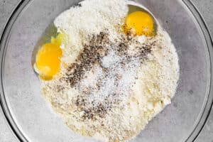 breadcrumbs, eggs, and seasonings in glass bowl