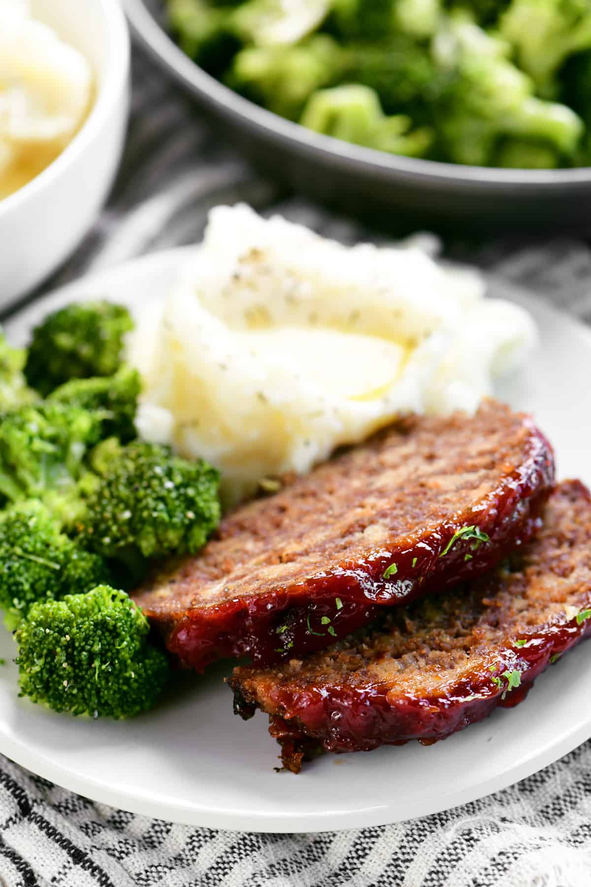 sliced meatloaf on a plate with broccoli and potatoes
