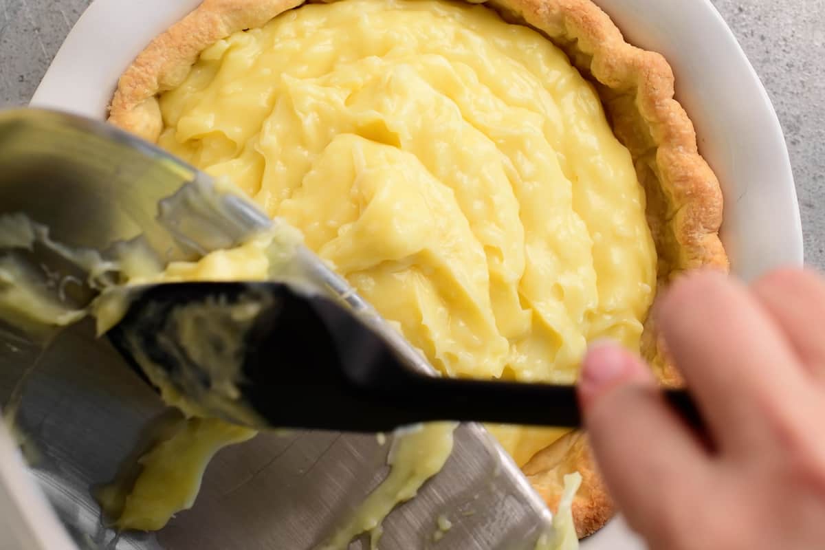 scraping pie filling into a bowl with a spatula
