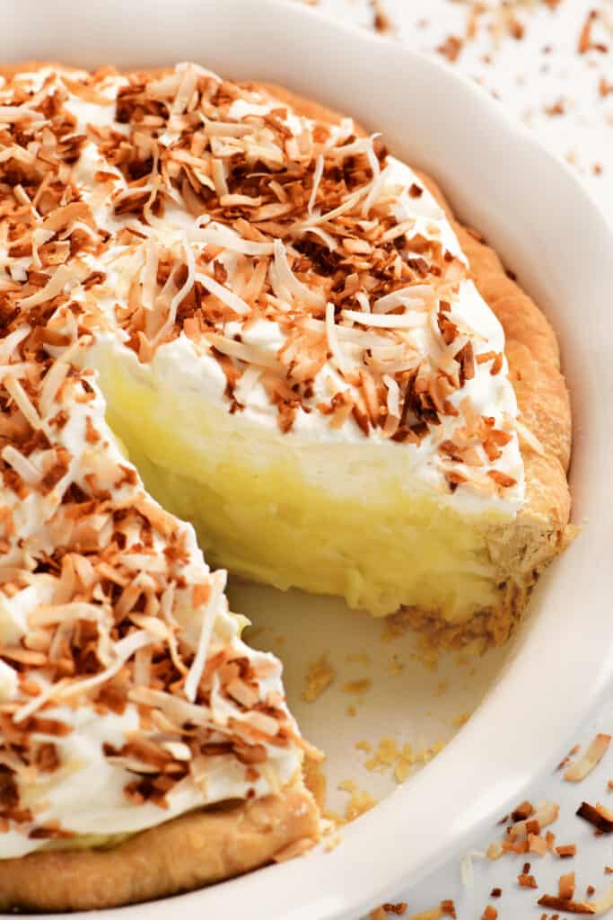 a coconut cream pie with a slice removed from the dish