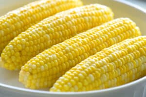 buttered corn on the cob on a white platter