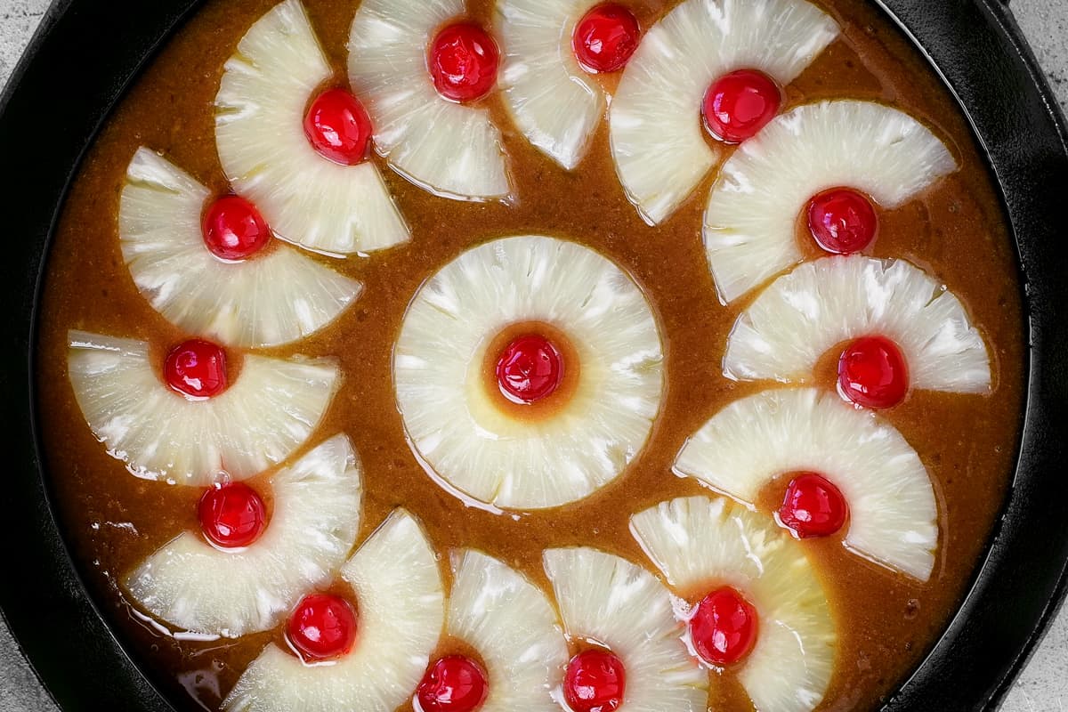 pineapple upside down cake batter and fruit in a skillet