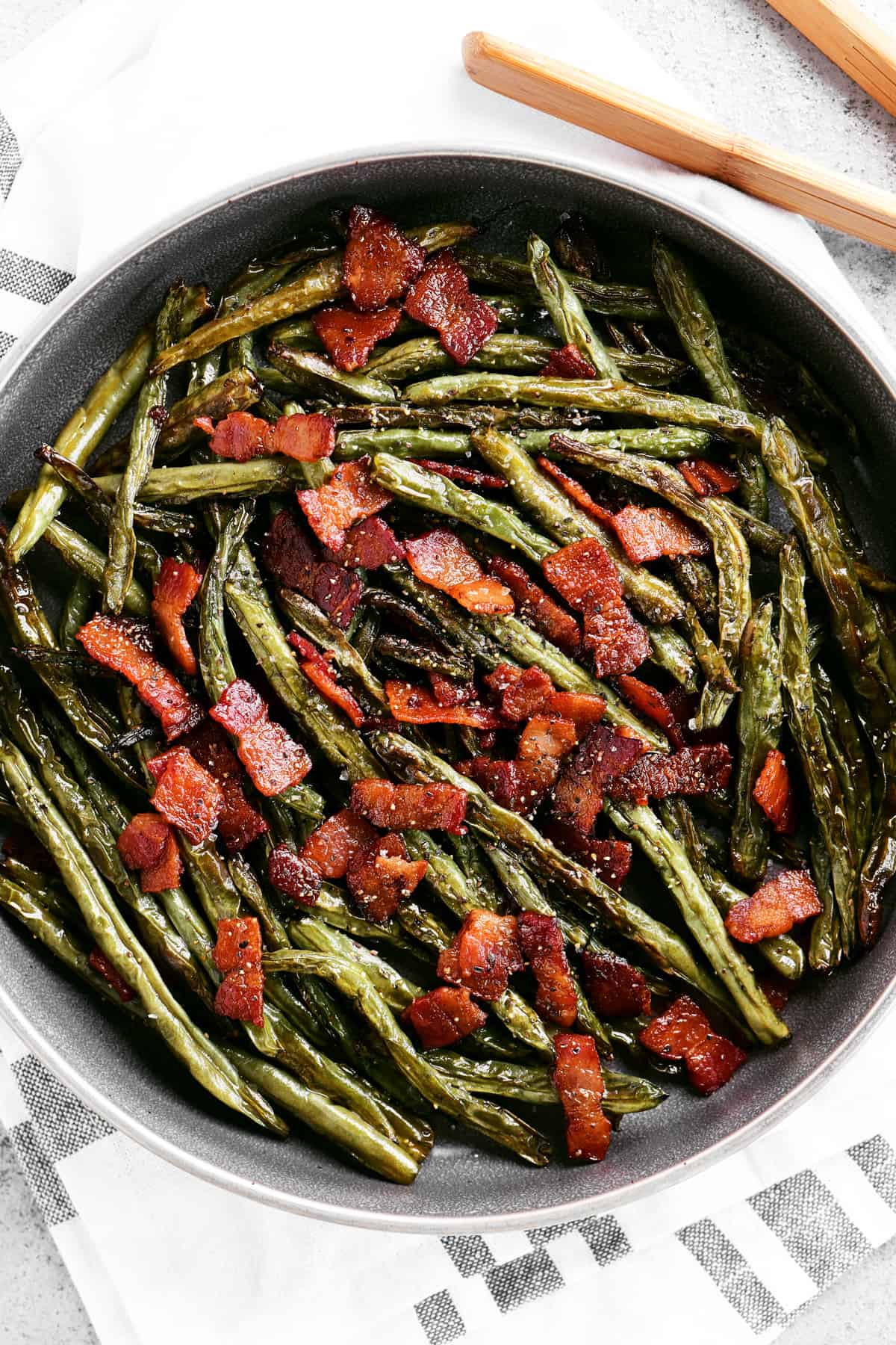 seasoned roasted green beans and bacon in a serving dish