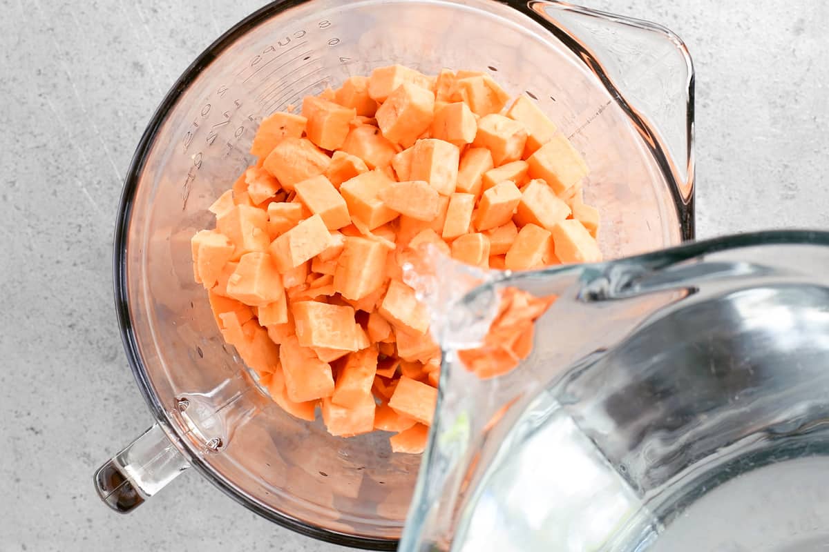 adding water to the bowl of sweet potatoes