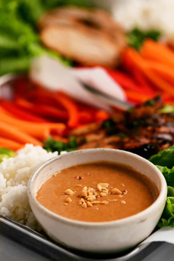 a bowl of peanut sauce on a tray of food
