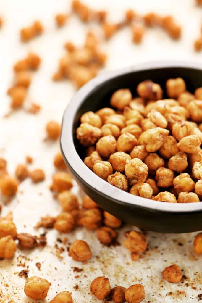 side view of a black wooden bowl filled with crunchy roasted chickpeas