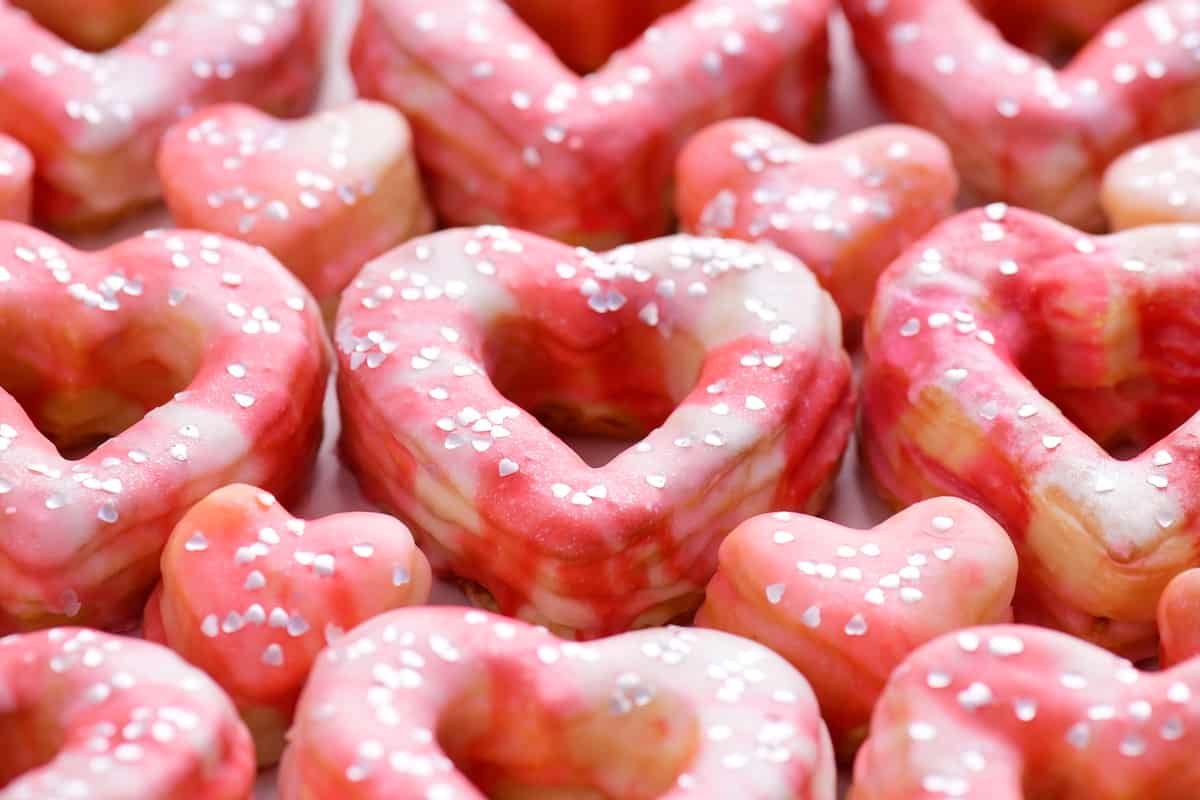 several heart donuts with pink glaze and silver sprinkles