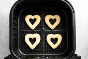 4 heart shapes of donut batter in the air fryer basked