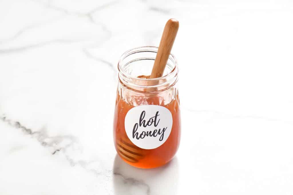 a jar of honey with a honey wand inside