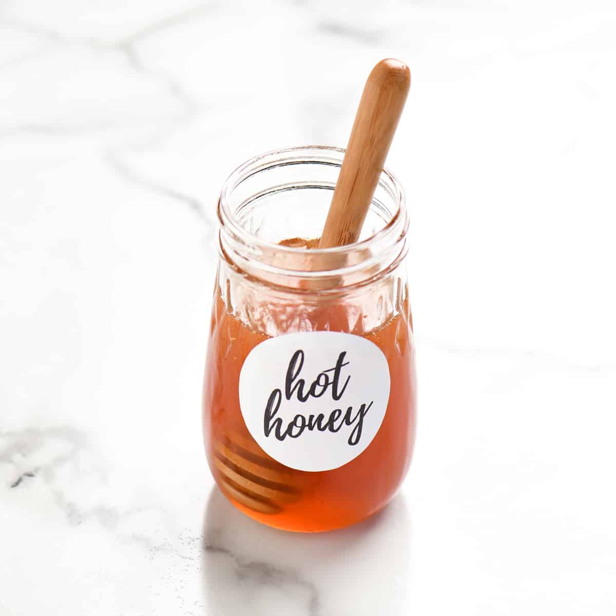 a honey wand in a small jar of hot honey
