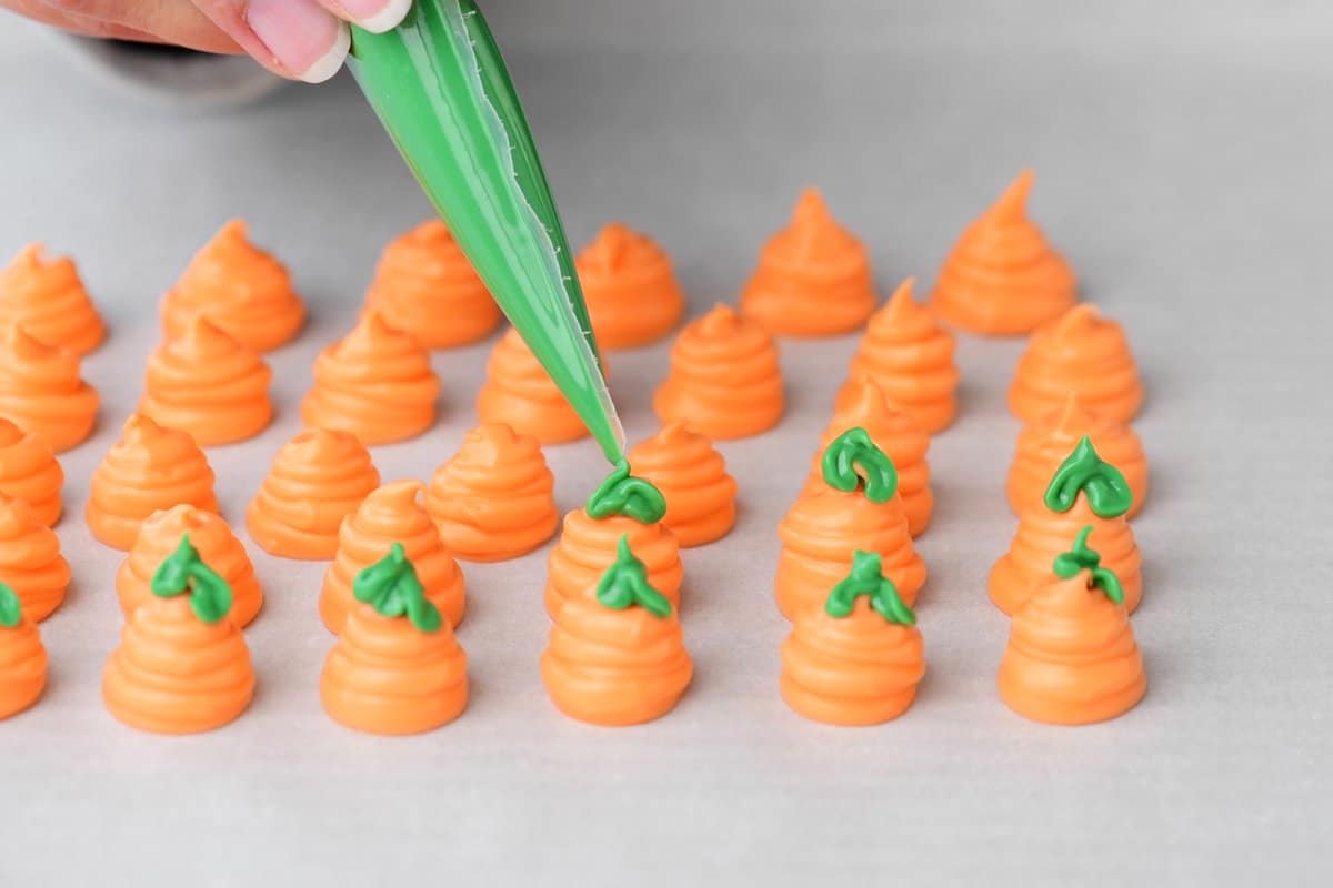 a hand shown piping green candy melt on to the carrot decorations