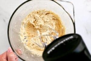 a mixer mixing frosting in a mixing bowl
