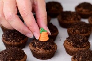 a hand shown adding the carrot decoration to the cookie cups
