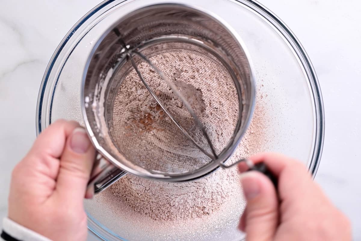 hands shown using a sifter to sift ingredients