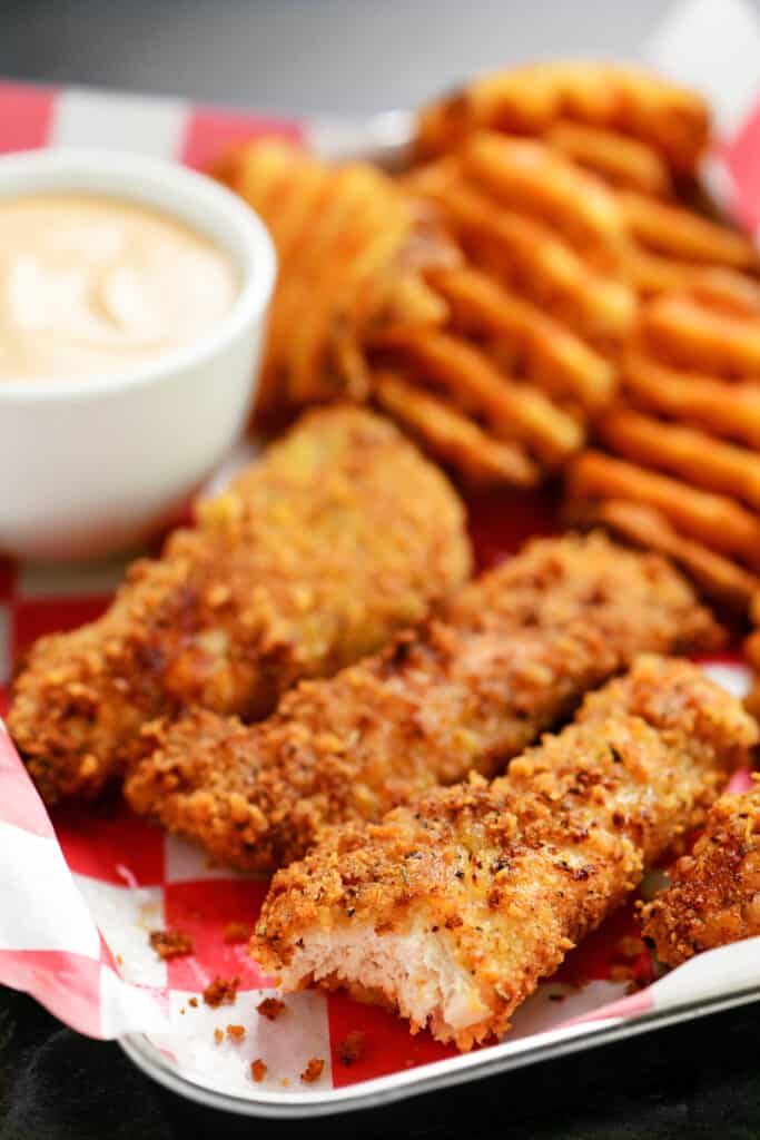 air fryer chicken tenders and waffle fries with dipping sauce on a tray