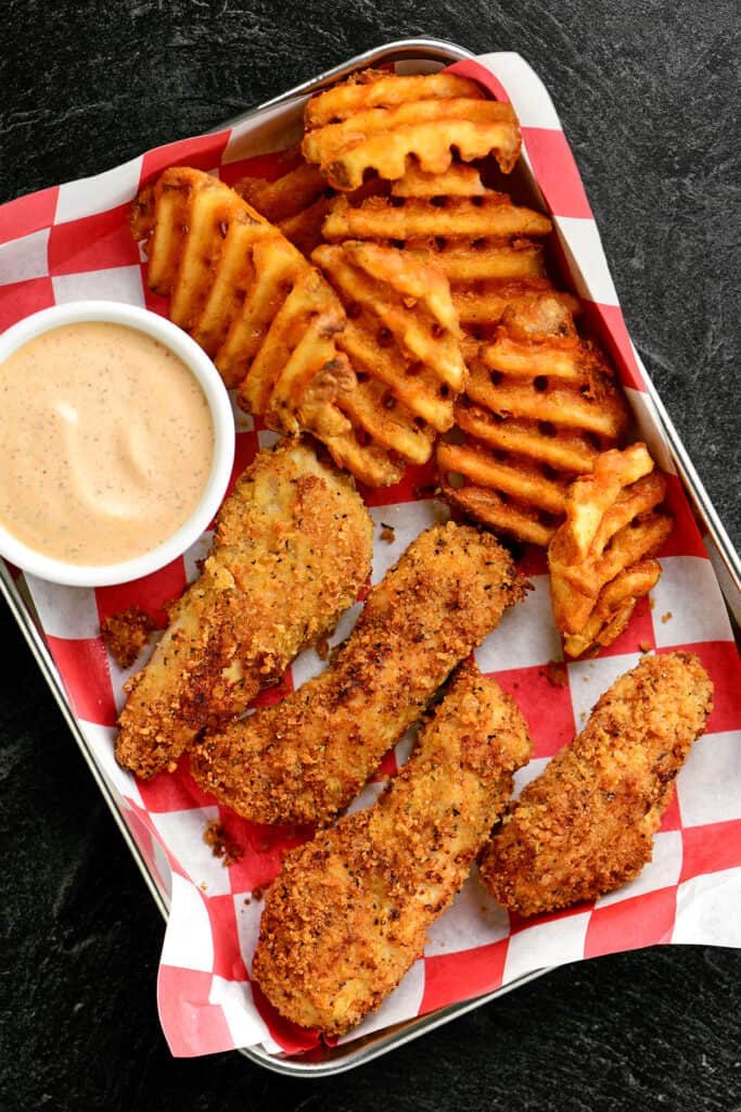 chipotle dipping sauce and chicken tenders with fries on a small tray