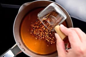 adding crushed red peppers to saucepan