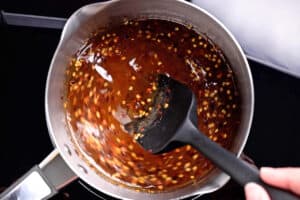 stirring hot honey with crushed red peppers in a saucepan