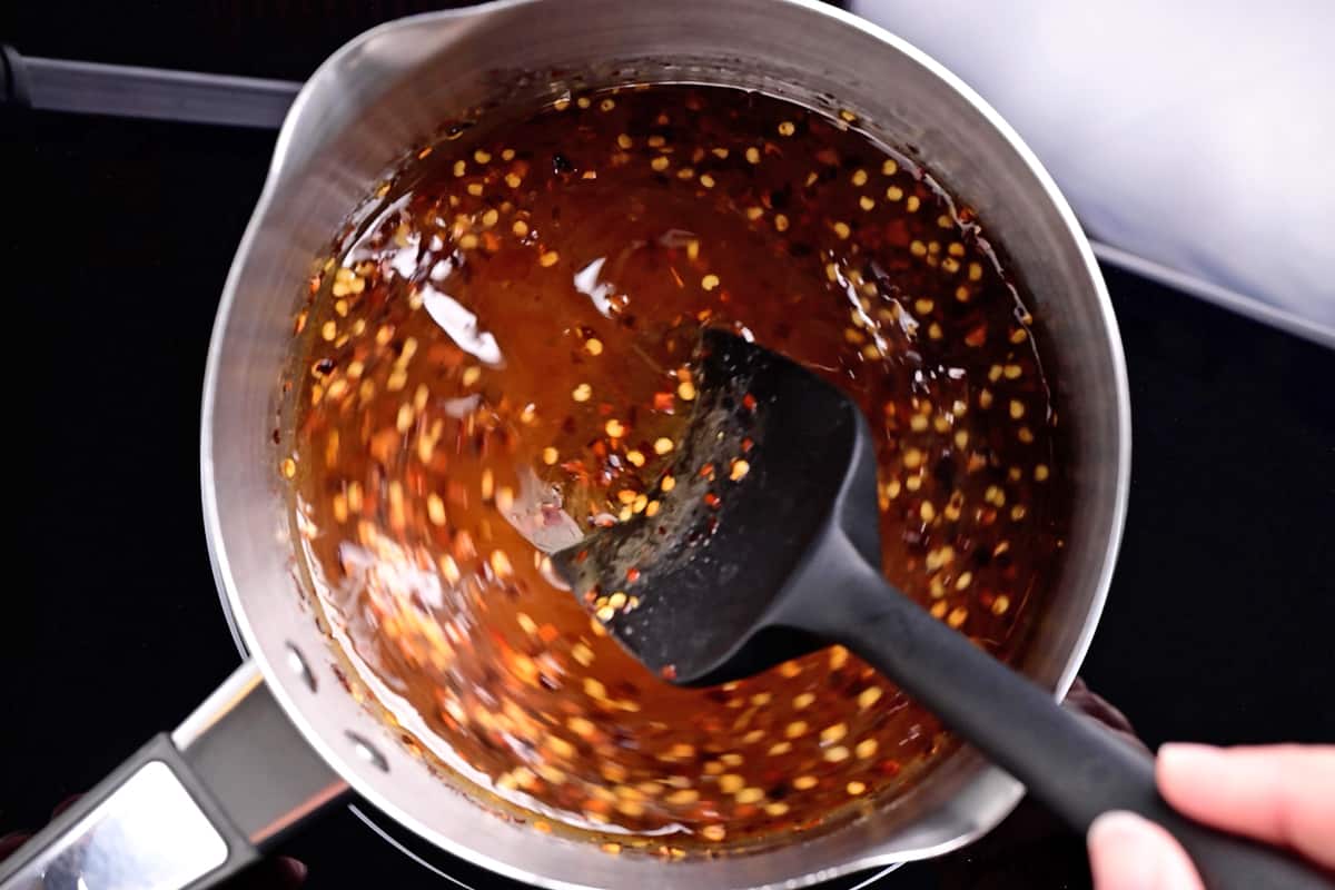 stirring hot honey with crushed red peppers in a saucepan