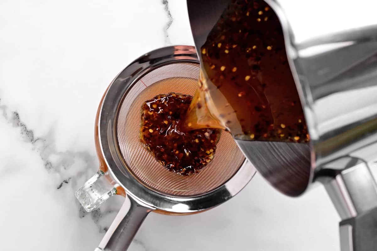 poring hot honey into a strainer