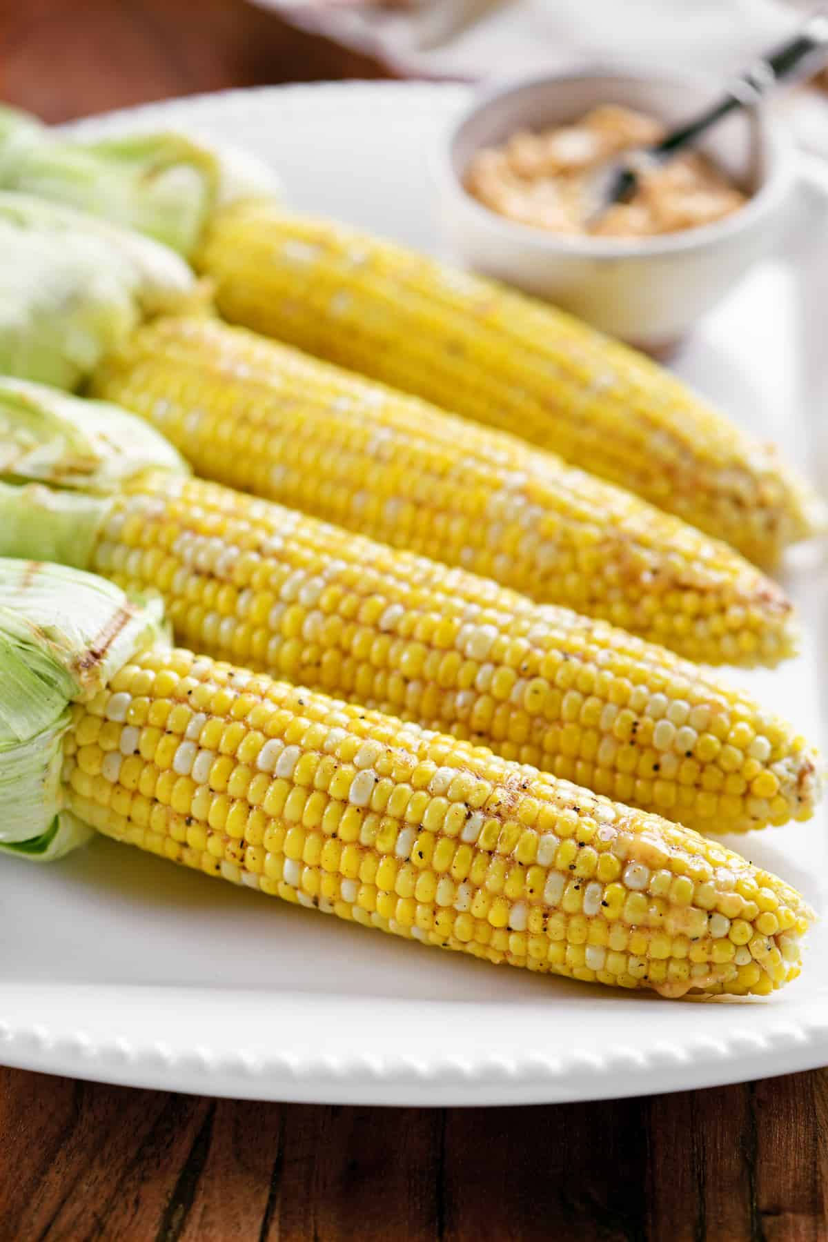 a platter with four cobs of corn on it
