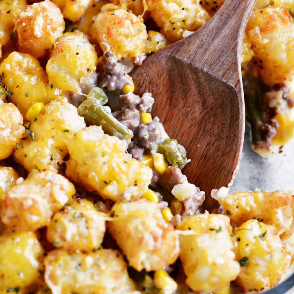 tater tot casserole with a wooden spoon