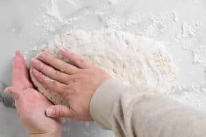 hands shaping dough on a counter top