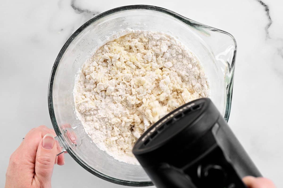 hands using a mixer to stir muffin batter ingredients